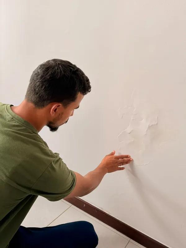 Eng. Eduardo em vistoria: pintura descolando na parede: sinal de umidade que precisa ser investigado